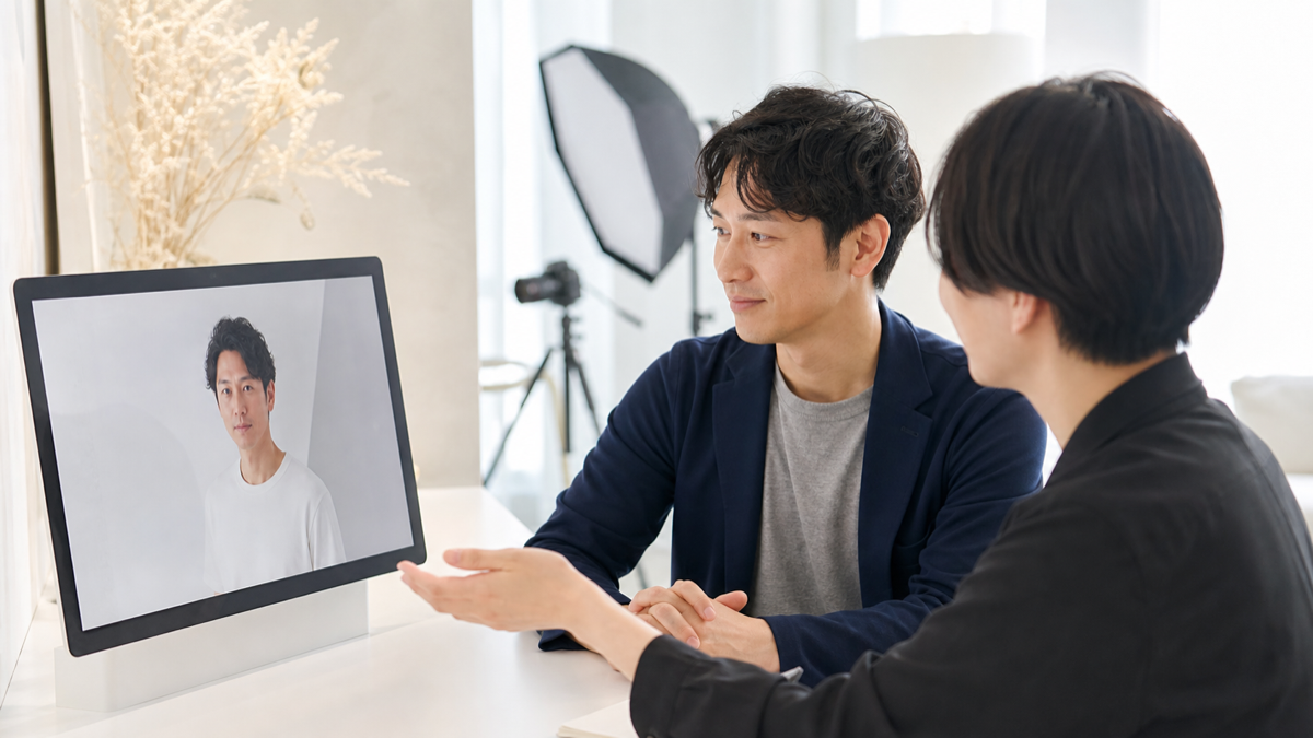 大阪の写真スタジオでプロフィール写真の自然なレタッチを相談する男性とスタッフ
