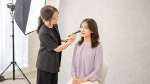写真スタジオで撮影前のヘアメイクを受ける女性