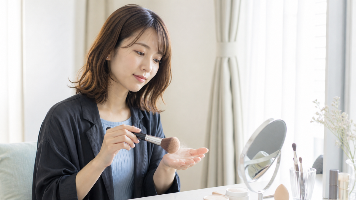 撮影前にブラシの余分なフェイスパウダーを落とす成人女性